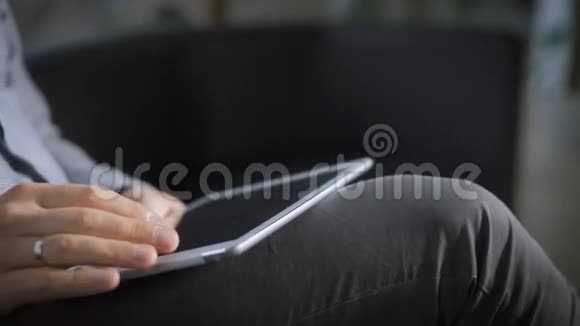 一个男人坐在沙发上浏览你的小工具上的社交网络上的新闻视频的预览图