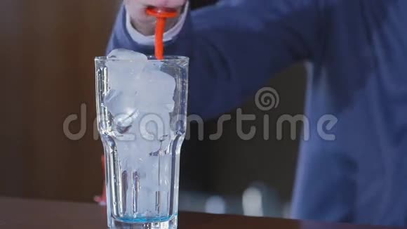 蓝色饮料倒入玻璃杯中加冰和鸡尾酒的杯子酒吧里的异国情调饮料慢动作视频的预览图