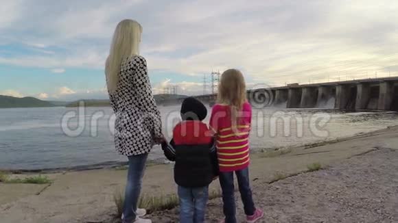 年轻的女人和两个孩子看着水电站慢动作视频的预览图