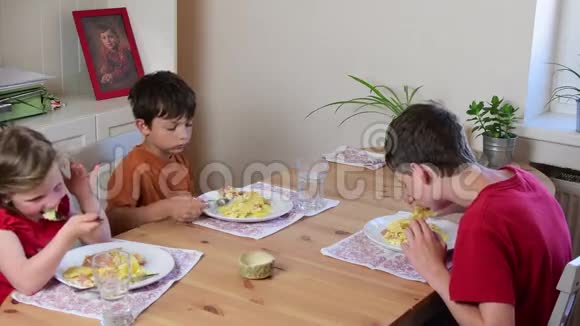 可爱的小女孩和她的兄弟们吃晚餐孩子们在厨房吃饭厨房里的女孩和男孩视频的预览图