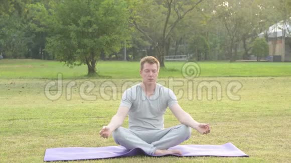 年轻的帅哥在公园冥想时放松视频的预览图
