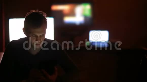 在电视屏幕背景下黑暗中看平板电脑的人视频的预览图