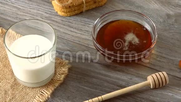 牛奶蜂蜜饼干和新鲜的小面包放在乡村的木桌上乡村早餐视频的预览图