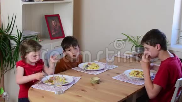 可爱的小女孩和她的兄弟们吃晚餐孩子们在厨房吃饭厨房里的女孩和男孩视频的预览图