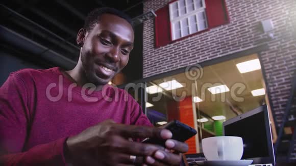 快乐的非洲商人坐在咖啡馆里用笔记本电脑工作的肖像视频的预览图