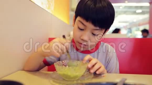 年轻的亚洲男孩在杯子里吃冰淇淋快乐的脸视频的预览图
