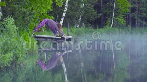 年轻女子在湖岸做瑜伽练习视频的预览图