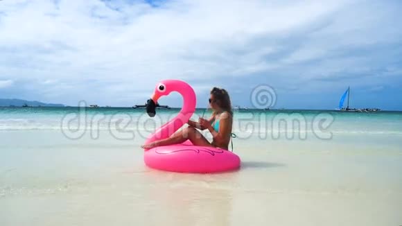 女孩漂浮在美丽的白色海滩上的充气床垫上上面有清澈的水视频的预览图