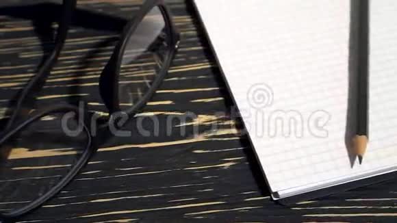 黑色木制背景上的眼镜铅笔和笔记本视频的预览图