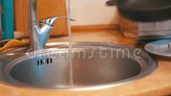 女人在家用厨房里用自来水清洗热煎锅慢动作视频的预览图