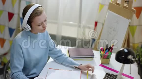 年轻有魅力的女人坐在桌子旁听音乐视频的预览图