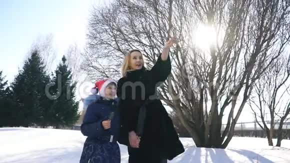 快乐的家庭妈妈和宝贝女儿跑在冬天在雪地里散步玩耍视频的预览图