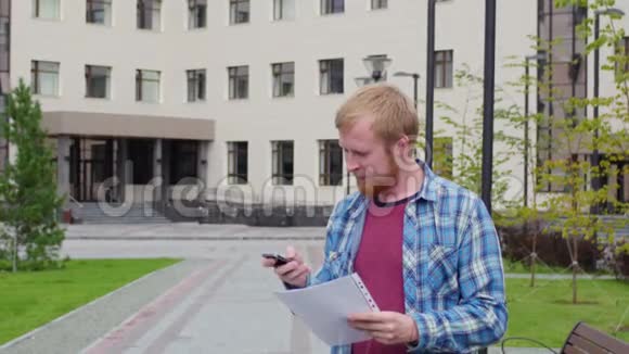 一个年轻的学生来到大学的背景下打电话拿着重要的文件视频的预览图