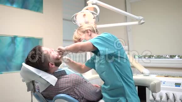 牙医检查病人的牙齿并与他交谈视频的预览图