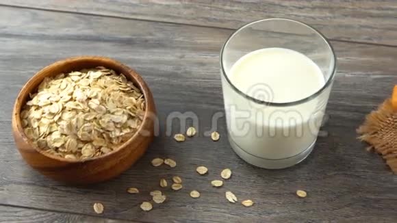 一碗燕麦片一杯牛奶和新鲜的自制面包在一张乡村木桌上视频的预览图