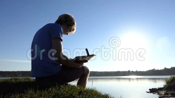 金发男人看着夏天湖岸上的家庭照片视频的预览图