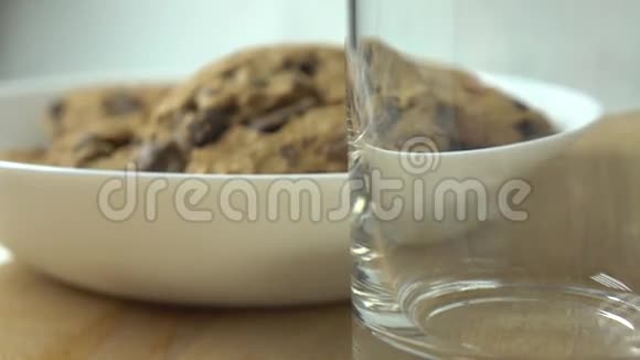巧克力饼干和牛奶倒在玻璃杯里4K型特写镜头视频的预览图