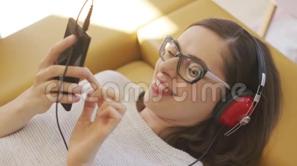 开朗的女人听音乐浏览智能手机视频的预览图
