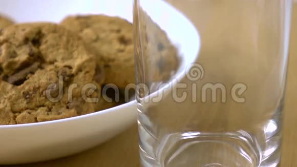 巧克力饼干和牛奶倒在玻璃杯里特写超慢动作镜头视频的预览图