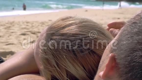 一个女人坐在沙滩上看着海洋躺在男人的胸前视频的预览图