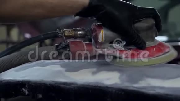 戴着黑色手套的人在车身服务特写镜头中使用空气砂光机视频的预览图