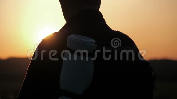 一个背着背包的男人在明亮的天空日落时的剪影太阳下山了旅行概念旅游旅行性质视频的预览图