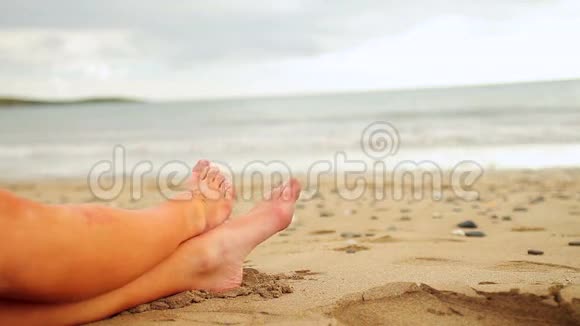 女人的双腿坐在海边视频的预览图