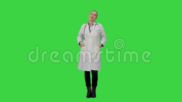 微笑着穿着实验室外套的漂亮女人在绿色屏幕上与相机交谈Chroma键视频的预览图