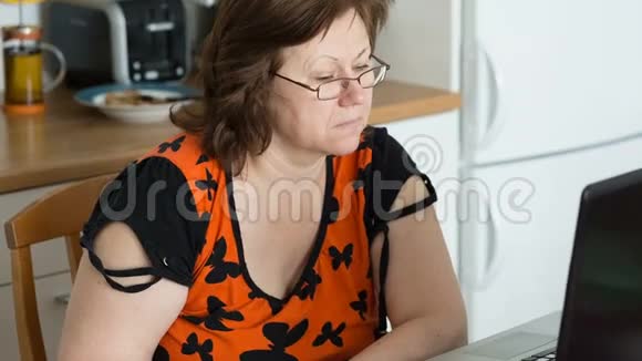 戴眼镜的中年妇女使用笔记本电脑视频的预览图