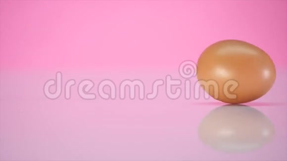 鸡蛋在粉红色背景的桌子上旋转视频的预览图
