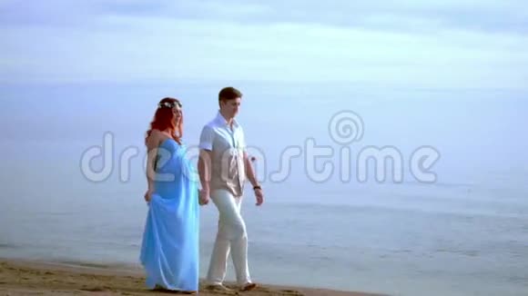 喜欢在海滩上散步的情侣怀孕的夫妇在海滩散步双人沙滩视频的预览图