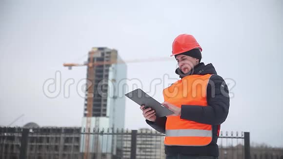 建筑设计师戴着头盔和橙色背心的工人背景是一名多层房屋起重机工人视频的预览图