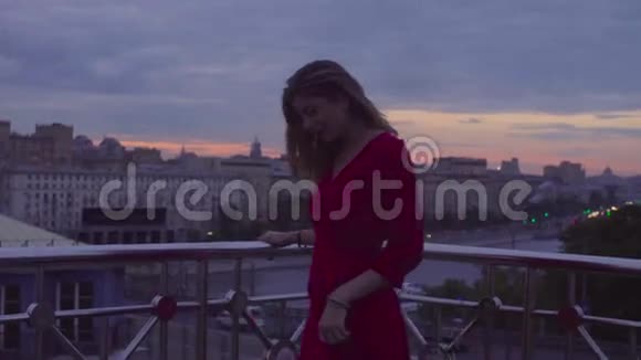 穿红色衣服的年轻女子站在栏杆旁视频的预览图
