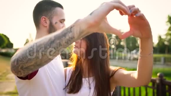 年轻一对相爱的情侣在日落时分用手做心的象征视频的预览图