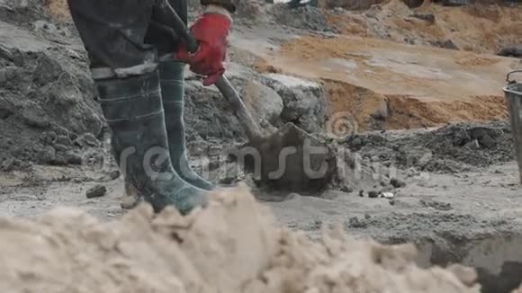 戴红手套的工人在建筑工地上用铲子收集水泥视频的预览图