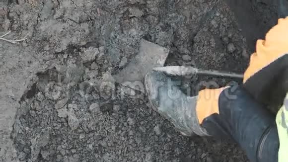 穿橙色安全帽的工人用铲子在碎石上挖泥土视频的预览图