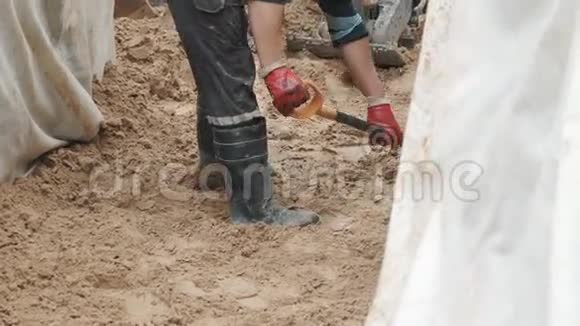橡胶靴中的慢速运动工人在沟槽中用铲平砂视频的预览图