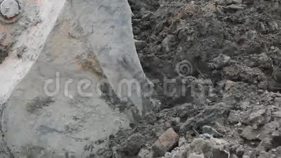 慢速挖掘机斗在土堆和泥土下拉混凝土板视频的预览图