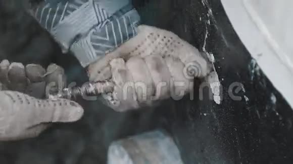 穿着工作手套和条纹夹克的人从混凝土中解开金属棒视频的预览图