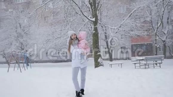 年轻的母女在公园的大雪中幸福地在一起视频的预览图