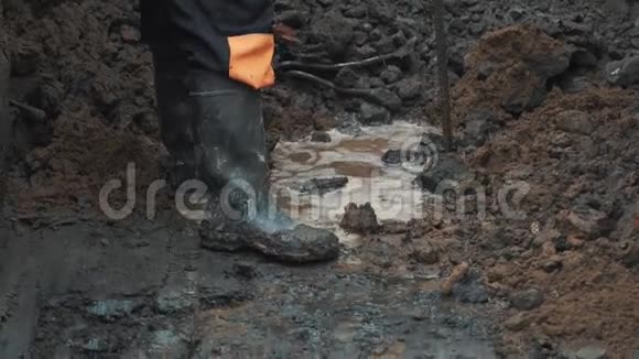 穿着橡胶靴的人用一块衔铁在泥坑里挖土视频的预览图