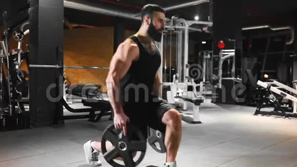 男人在健身房里抽肌肉力量锻炼健身俱乐部里的运动员白种人留胡子的男人在抽视频的预览图