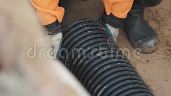 工作手套的工人橡胶靴把塑料管放在沙子上测量视频的预览图