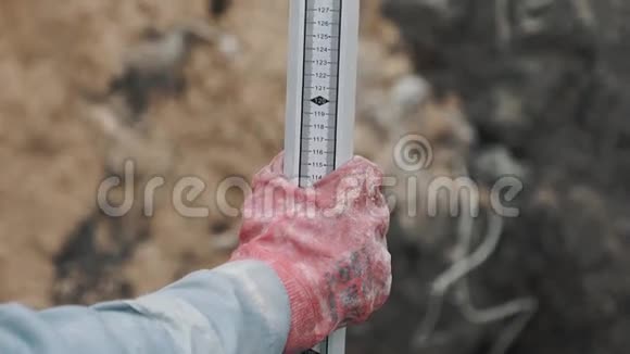 穿红色橡胶手套的工人拿着垂直的长工业金属尺视频的预览图