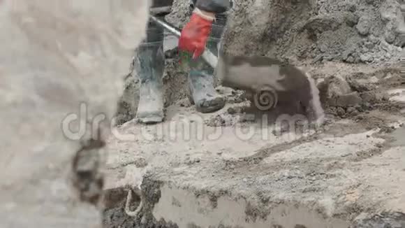 在建筑工地用铲子收集水泥的胶靴工人视频的预览图