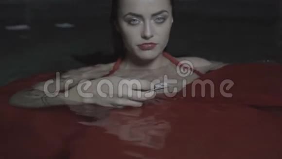 晚上在室外游泳池穿红色裙子的美丽迷人女人视频的预览图