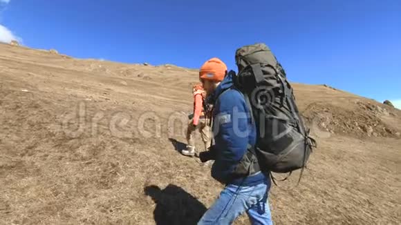 两个戴着帽子和太阳镜背包的游客摄影师带着相机在黄草上山视频的预览图