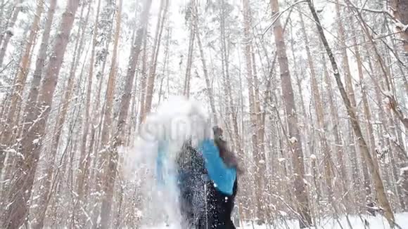 在冬天的森林里向空中撒雪的年轻女子视频的预览图