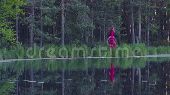 在湖边的森林里散步的年轻女子视频的预览图