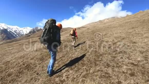 两个戴着帽子和太阳镜背包的游客摄影师带着相机在黄草上山视频的预览图